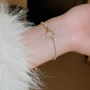 Gros plan sur un élégant bracelet en or avec pendentifs cœur et infini en zircons.