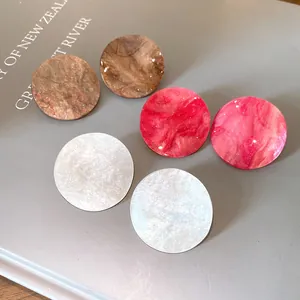 Macro detail view of elegant round acrylic marble stud earrings in various marble patterns.