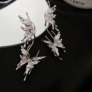 Detailed view of silver liquid metal butterfly earrings with textured wings on black silk