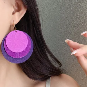 Detailed close-up view of oversized layered purple wood circle drop earrings worn on an ear