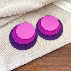 Detailed view of bohemian layered purple wooden disc drop earrings on textured linen background.