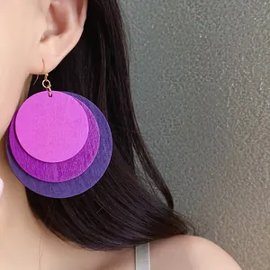 Close-up detail of three-layered purple wooden circle earrings showing natural grain texture