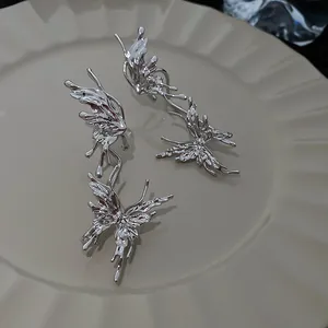 Detail view of silver-tone liquid metal butterfly earrings with wrinkled texture.