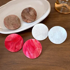Close-up of three pairs of colorful marble-textured acrylic circular stud earrings.