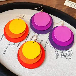 Close-up detail of layered wooden circle drop earrings in vibrant red, orange, and purple hues.