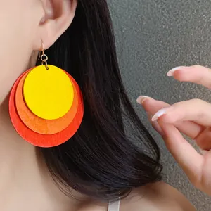 Detail of vibrant three-layer round wooden earrings in yellow, orange, and red