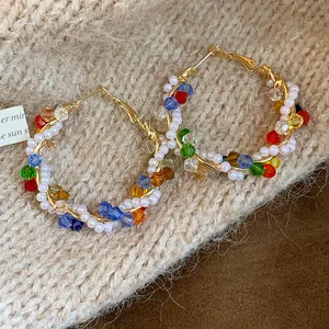 Vista detallada de elegantes pendientes de aro dorados con cristales de colores y perlas