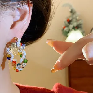 Pendientes de aro con cuentas de colores y perlas blancas usados por modelo asiática