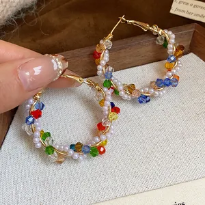 Primer plano detallado de pendientes de aro con perlas blancas y cristales de colores