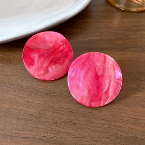 Detailed close-up of pink marbled acrylic round stud earrings with a fine glitter finish