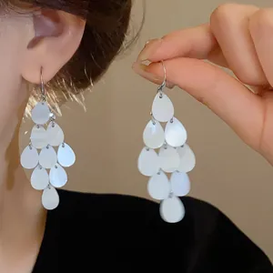 Elegant waterdrop tassel earrings with pearlescent finish on model, detail view.