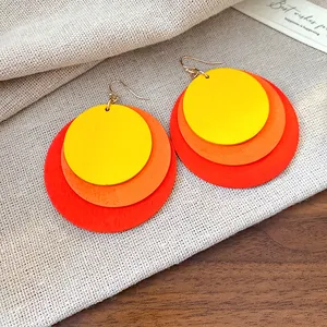 Macro view of layered colorful circular wooden drop earrings with gold hook closure