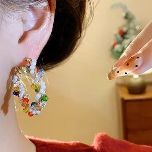 Primer plano de un pendiente de aro con cuentas de colores y perlas blancas finas