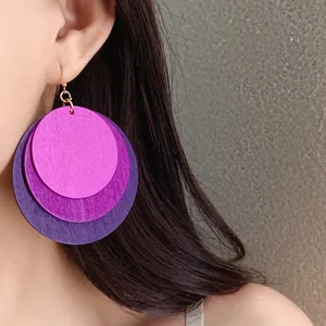 Detailed close-up view of vibrant layered round wooden drop earrings worn on a model ear