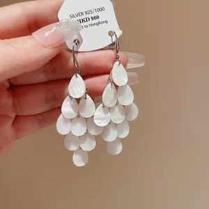 Close-up view of elegant white water drop tassel earrings with a pearlescent finish