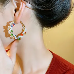 Primer plano de pendientes de aro con cuentas de colores estilo dopamina en modelo.