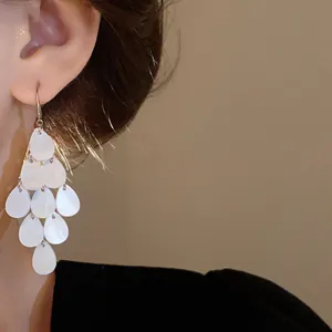 Close-up view of white teardrop tassel earrings featuring elegant Korean style and ear hooks.