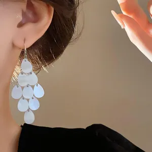 Elegant waterdrop tassel drop earrings with white pearlescent finish in close-up view