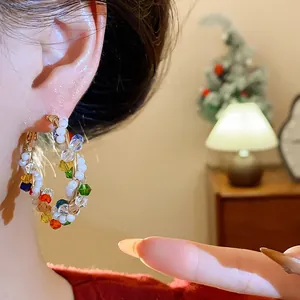 Primer plano de un pendiente de aro con perlas de colores en un entorno acogedor.