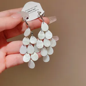 Detail view of elegant teardrop tassel earrings with shimmering shell-like finish