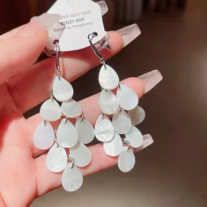 Elegant white water drop tassel earrings with shell-like texture and silver hooks.