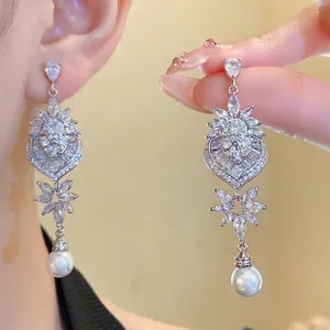 Eleganti orecchini ad ago in argento con design a foglia e cuore e pendenti di perle bianche.
