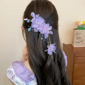 Vue détaillée d'une pince à cheveux à fleurs en tissu violet avec glands soyeux