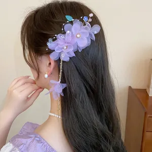 Détail d'une pince à cheveux en tissu violet avec perles et un long gland élégant