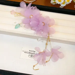 Vue détaillée d'une élégante pince à cheveux fleur en tissu violet avec glands en perles.