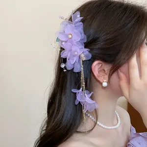 Vue détaillée d'une pince à cheveux fleur en tissu violet avec perles et longs glands dorés