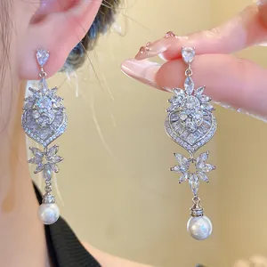 Dettaglio orecchini a cuore in argento con zirconi scintillanti e gocce di perla bianca