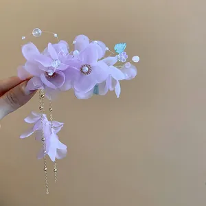 Gros plan d'une élégante pince à cheveux en tissu violet avec perles et détails de pompons