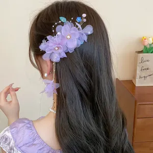 Vue détaillée d'une élégante pince à cheveux fleur en tissu violet avec de longs glands en perles.