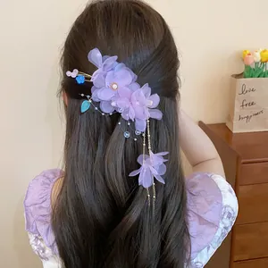 Gros plan d'une pince à cheveux fleur en tissu violet avec de longues franges élégantes