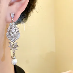 Dettaglio di eleganti orecchini pendenti in argento con cuore e perla per stile donna.