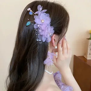 Vue détaillée d'une élégante pince à cheveux en tissu violet avec perles et glands