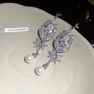Dettaglio di orecchini a cuore e foglia con pietre brillanti e perle