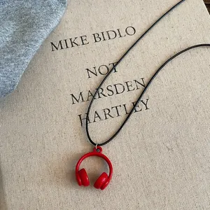Minimalist red headphone pendant necklace with black cord for a casual look.