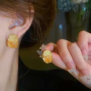 Detailed shot of oval crystal earrings with golden border and warm amber texture