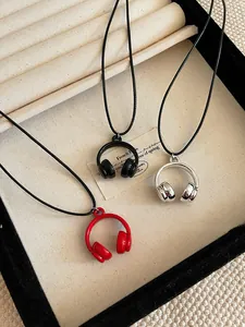 Close-up detail of mini headphone pendant necklaces in red, black, and silver finishes.