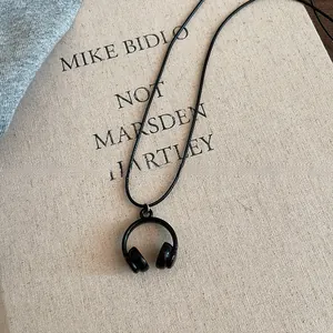 Macro detailed view of a matte black mini headphone pendant necklace on a linen book