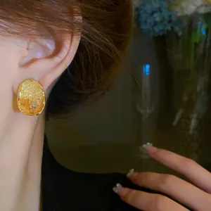Close-up view of an elegant oval crystal stud earring with golden bezel