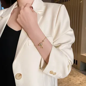 Vue détaillée d'un bracelet en or avec un pendentif cœur et un charme cylindrique.