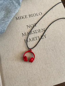 Detailed macro view of a red enamel headphone pendant on a sleek black cord necklace