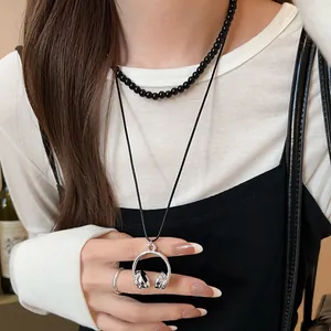 Detail shot of a silver-toned headphone pendant necklace worn by a model in casual style