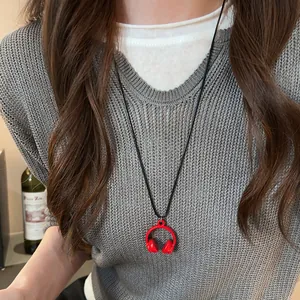 Detailed shot of a creative mini red headphone pendant necklace worn on a grey knit sweater