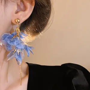 Close-up of elegant blue mesh flower dangle earring worn by a model in soft lighting