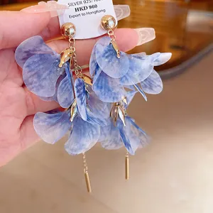 Close-up of blue mesh flower petal dangle earrings with gold studs and silver needles