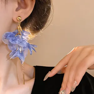 Close-up detail showing the blue mesh flower petal drop earrings with gold-tone tassel