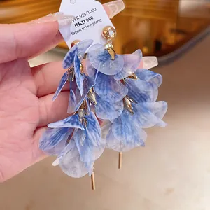 Close-up detail of ethereal blue gauze flower earrings featuring delicate gold accents